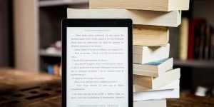 eBook-Reader vor einem Bücherstapel